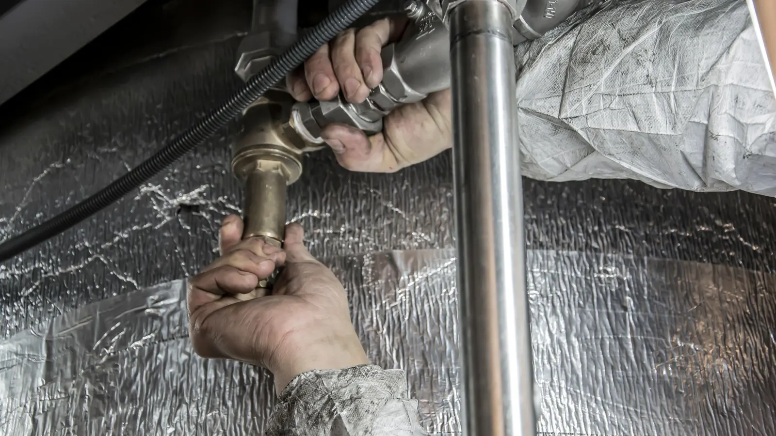 Water heater installation in Lynn, MA with a plumber connecting supply pipes